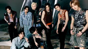 a captivating group photo of the south korean boy band seventeen. the members are striking poses, showcasing their edgy fashion style against a dark, moody background. their attire is a mix of leather jackets, ripped denim, and statement tops, creating a strong visual impact. the image features dynamic lighting that highlights individual members and the overall intensity of the scene. it is a promotional shot, likely for an album or music video.