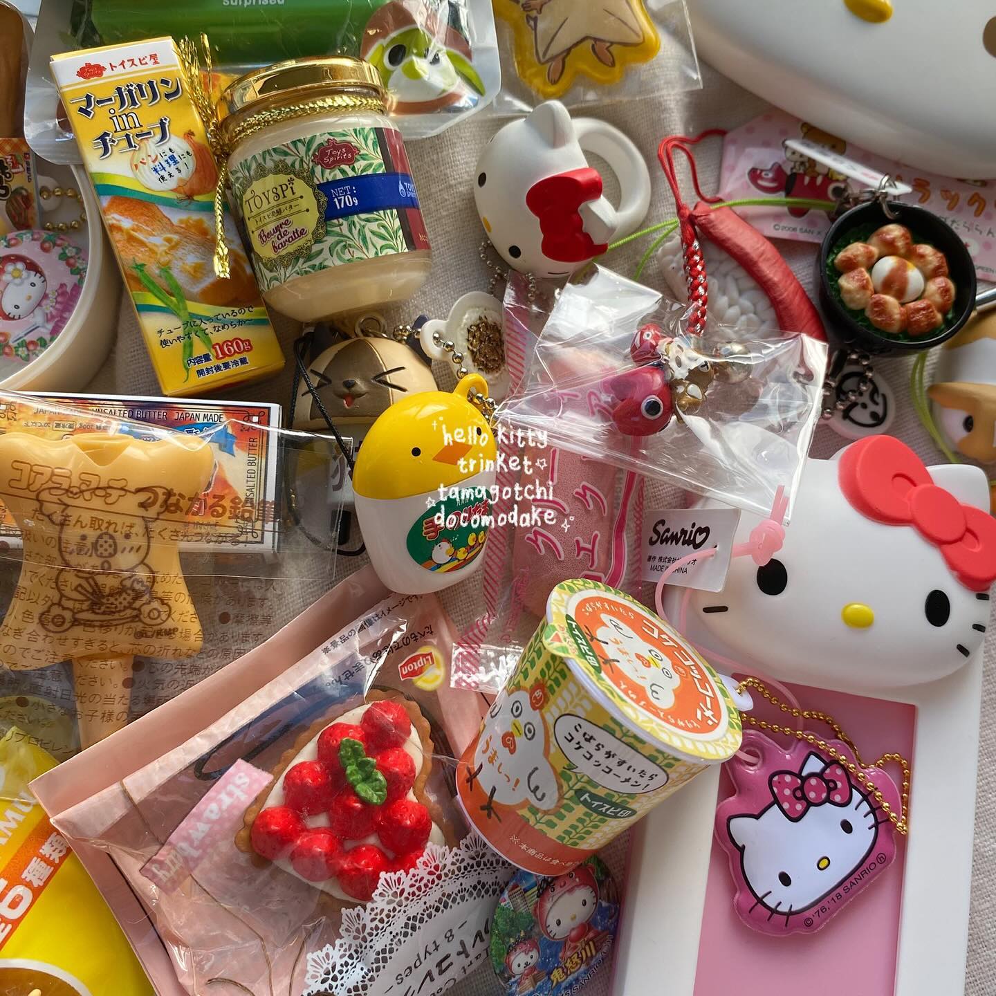the image shows a collection of hello kitty and sanriothemed trinkets and foodthemed accessories. there are keychains, miniature food items like a strawberry tart and a cup noodle, and packaged japanese snacks such as margarine. the image is filled with various cute, colorful items, suggesting a hobby or collection of miniature and kawaiistyle products.