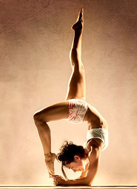 a woman is doing a challenging yoga pose, bending backwards with her leg up and her arms on the ground. she is focused and looks strong and flexible.