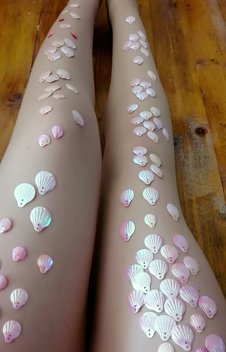 this is a photo of a person's legs covered in iridescent pink and white shell shaped sequins, creating a mermaid look.