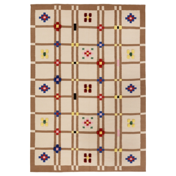 a tan, brown, and cream rug with a geometric, floral, and square pattern is displayed. the pattern creates a quiltlike aesthetic, with various floral designs distributed across the grid.