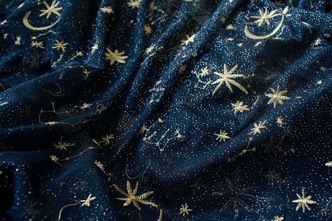 a closeup shot of a dark blue fabric with gold star and moon embroidery. the fabric is wrinkled and has a slight sheen.content: fabricpeople: no peopleenvironment: indoorslighting: softperspective: closeupkw: stars, moon, fabric, texture, embroidery, dark blue, gold, night sky, celestial, dreamy, magical, mystical, ethereal, romantic, whimsical, feminine, elegant, luxurious, soft, delicate, sheer, tulle, mesh