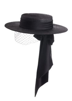 a black hat with a wide brim. the hat has a veil and a bow. it is an elegant hat for a formal event.  the hat is worn by a lady.