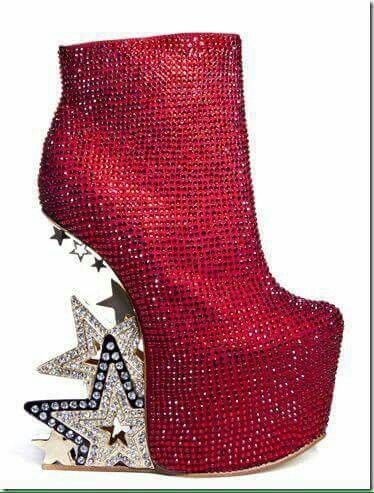 a red platform bootie with a wedge heel decorated with star designs. the bootie is covered in rhinestones. the stars on the heel are silver and black.