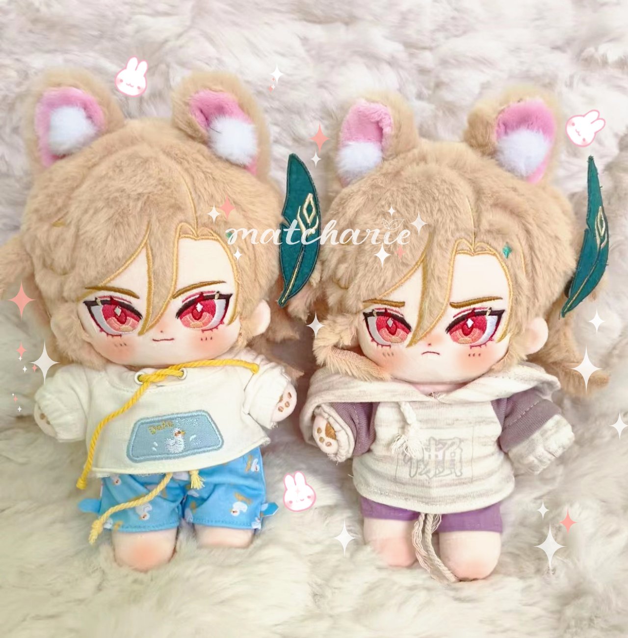the image shows two cute plush dolls, each wearing a different outfit. both dolls have brown fluffy hair and big, expressive eyes. the doll on the left is wearing a white hoodie with blue shorts and a small blue and white design on the front of the hoodie. the doll on the right is wearing a creamcolored hoodie with purple shorts and a large, white kanji character printed on the front. the dolls are both smiling and have a happy expression on their faces. the background is a fluffy white blanket. the dolls are handcrafted and are great for adding a touch of kawaii decor to a child's bedroom or any space. they are also perfect as a gift for friends and family who appreciate anime and kawaii style.
