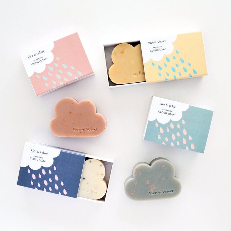 the image shows five different cloudshaped soaps, all made by vice & velvet. the soaps are packaged in simple, minimalist boxes with a cloud and raindrop design. the boxes are all different colors, with a pink, blue, green, yellow, and a brown soap.