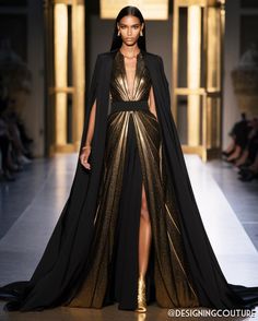 a fashion model walks down a runway, wearing a stunning black and gold gown. the dress features a black cape and a gold metallic bodice with a long, flowing skirt. she completes the look with matching black accessories, including jewelry and shoes. her makeup and hair are perfectly done, enhancing her natural beauty and adding to the overall elegance of the outfit. the model's confident and elegant pose showcases the gown's luxurious design and emphasizes its intricate details. the backdrop features a goldenhued setting, creating a striking contrast with the model's outfit and adding a touch of grandeur to the scene. the overall image exudes high fashion and luxury, capturing the essence of an exclusive runway event.