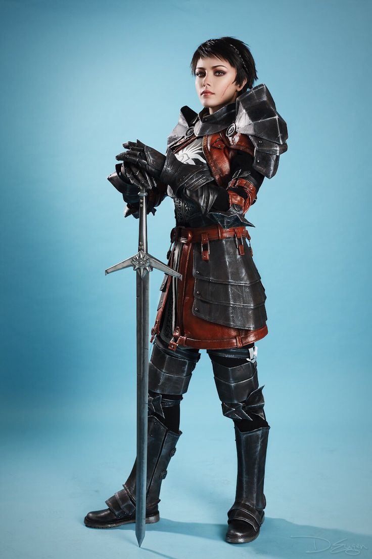 the image showcases a meticulously crafted cosplay of a female knight, possibly inspired by the dark souls series.  she is standing against a light blue background, holding a large sword.  her armor is detailed and appears to be made of leather and metal, predominantly dark in color with reddishbrown accents on the midriff. the knight's pose is confident and strong, conveying a sense of power and readiness. the overall image quality is high, suggesting a professional photo shoot.