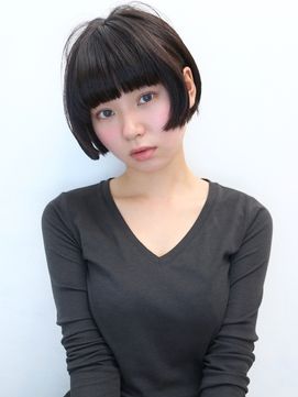 a young asian woman with short black hair. her hair is styled in a blunt bob with straight bangs that cover her forehead. she is wearing a black longsleeved shirt.