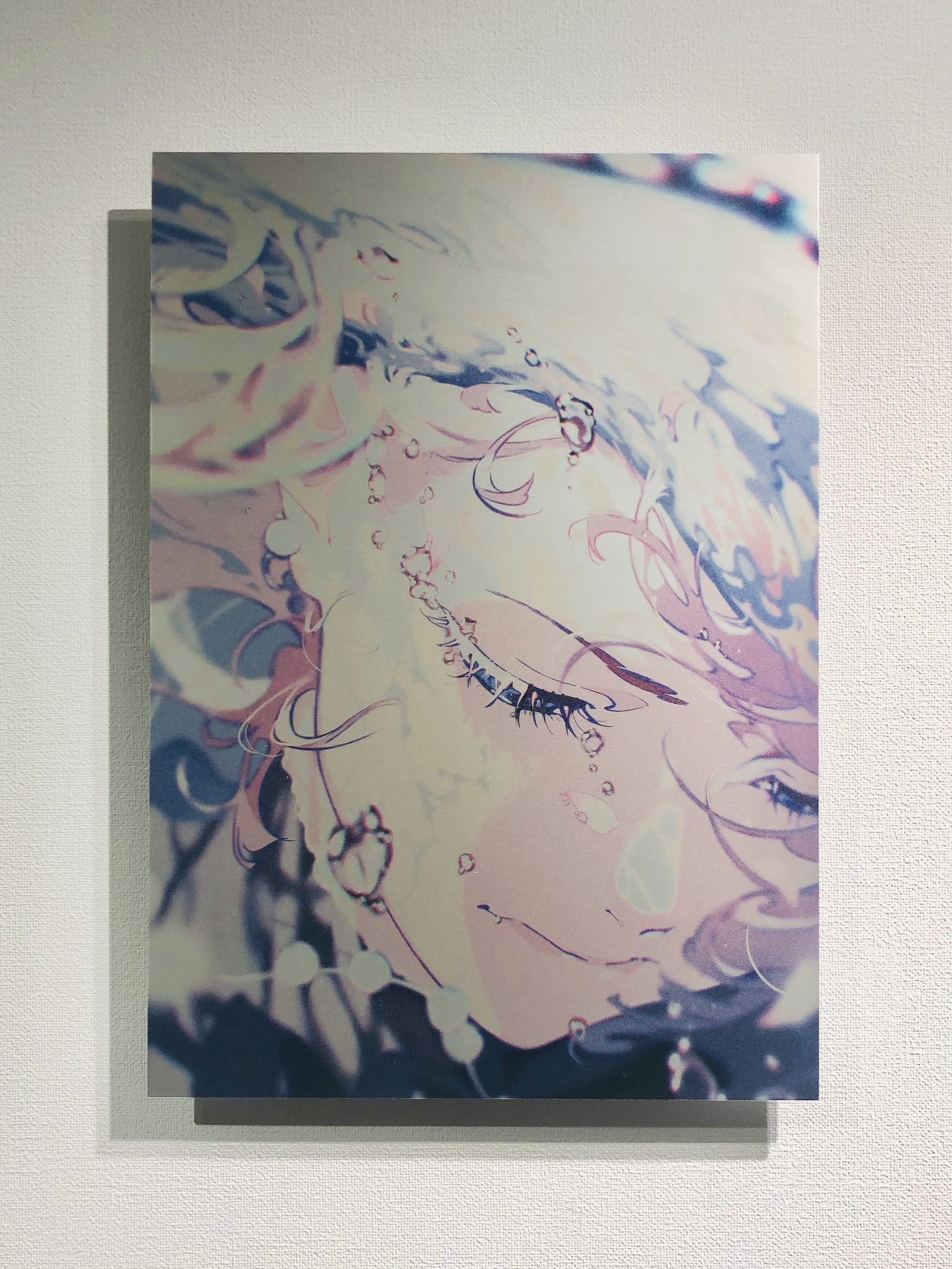 an animestyle illustration of a young woman with blonde hair and closed eyes. the art style is soft and dreamy, with a focus on light and shadow. the woman is surrounded by bubbles, suggesting she may be underwater.  the illustration is printed on a metallic or pearlescent paper that gives it a subtle sheen.