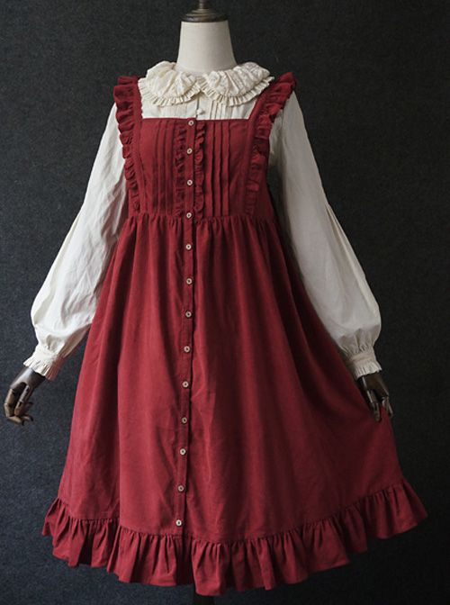 a fulllength image of a red corduroy dress with ruffles on a mannequin. the dress is styled in the lolita fashion and features a white blouse with a peter pan collar worn underneath. the dress has a square neckline, buttonup front, and a ruffled hem. the background is dark grey.