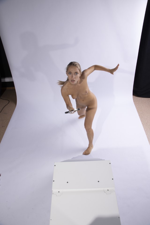 a full shot of a nude woman holding a lightsaber in a studio with a white background.