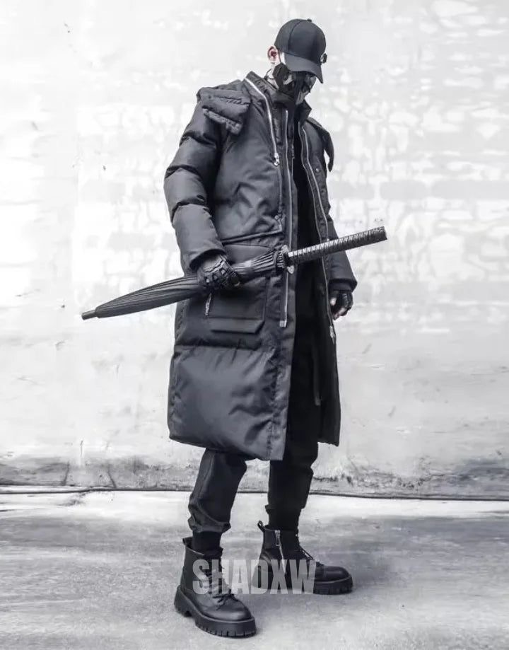 a man in a black puffer coat and black boots stands on a sidewalk, holding a black umbrella. he's wearing a black hat and face mask.  the outfit and accessories are trendy and edgy.