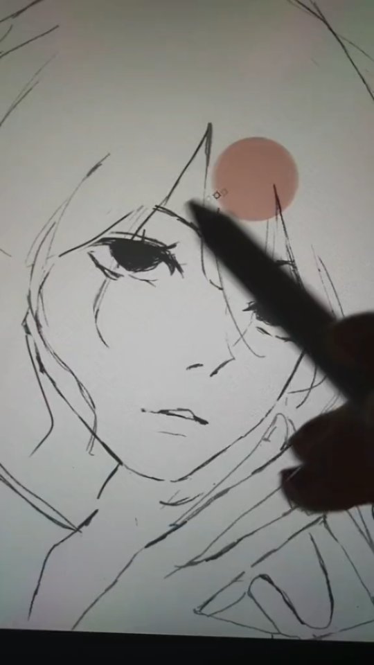 a closeup shot of a hand holding a stylus, drawing the face of an animestyle girl on a digital tablet. the drawing is still in progress, with visible sketch lines and shading. the artist's hand partially obscures the drawing, and a pinkishbeige circle is visible on the tablet, likely a guide or reference for color. the overall style is loose and expressive, characteristic of quick sketches.