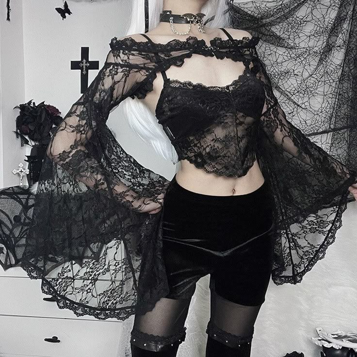 a woman is posing in a gothic fashion outfit, consisting of a black lace top with bell sleeves, black shorts, stockings, and a choker. the background features gothicthemed decorations such as a cross, black roses, and other elements of a dark aesthetic. the woman has white hair and is styled in an edgy and dark fashion.