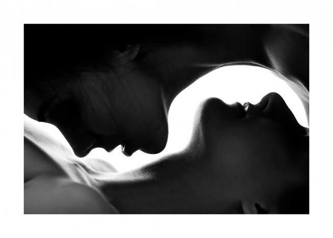 the image is a black and white closeup photograph of two women in a sensual embrace.  their bodies are intertwined, and their faces are close together, suggesting a kiss.  the lighting is dramatic, creating strong contrasts between light and shadow, emphasizing the curves of their bodies. the composition is almost symmetrical, with the two figures forming a shape reminiscent of the yin and yang symbol. the overall mood is intimate, passionate, and artistic.