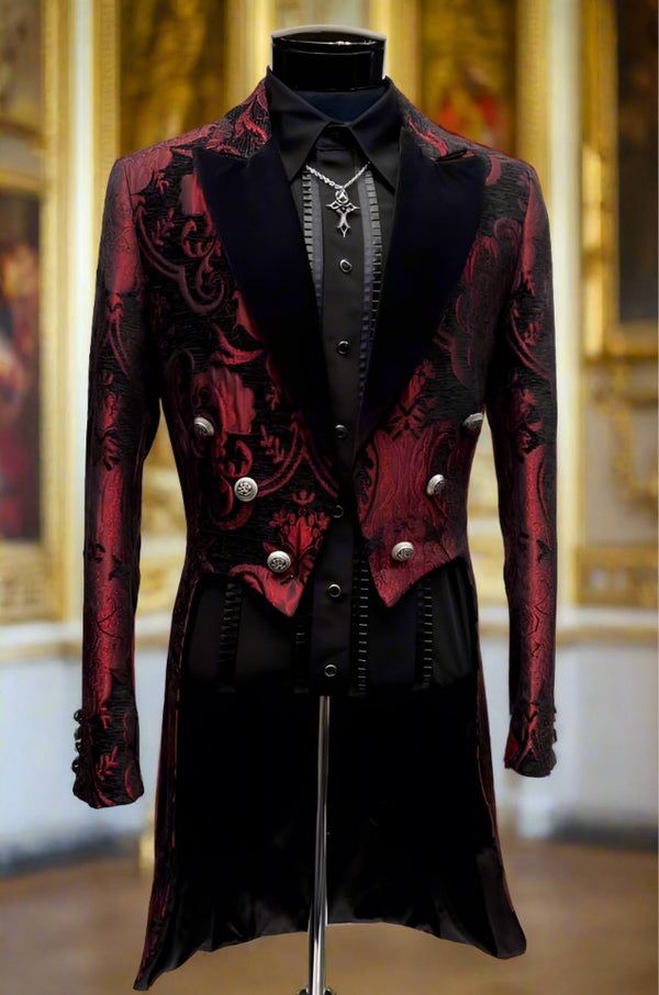 a mannequin is displaying a striking red and black patterned tailcoatstyle suit, complete with a black shirt, tie, and cross pendant. the jacket features velvet lapels and silver buttons, showcasing intricate design details.