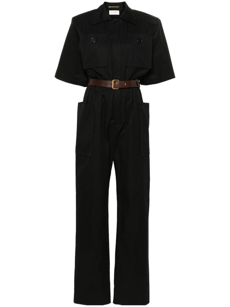 a black jumpsuit with a classic collared shirt design, short sleeves, and a belt. it features two large flap pockets on the front and a slimfitting silhouette. the fabric is smooth and tailored.