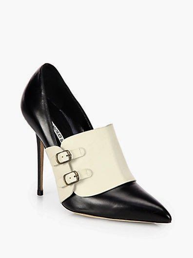 a black and white manolo blahnik pointedtoe high heel dress shoe is displayed in a studio setting. the shoe is made of leather and has a white flap over the toe box with two small buckles. the heel is stiletto style. the background is plain white.