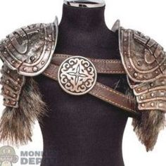 a closeup of shoulder armor mounted on a black mannequin. the armor is primarily silver with a distressed, antique finish and features multiple layered plates. brown leather straps crisscross the chest, held together by a large, decorative metal medallion with a swirling design and a central fourpointed star. fluffy brown fur trim accents the bottom of each shoulder piece.