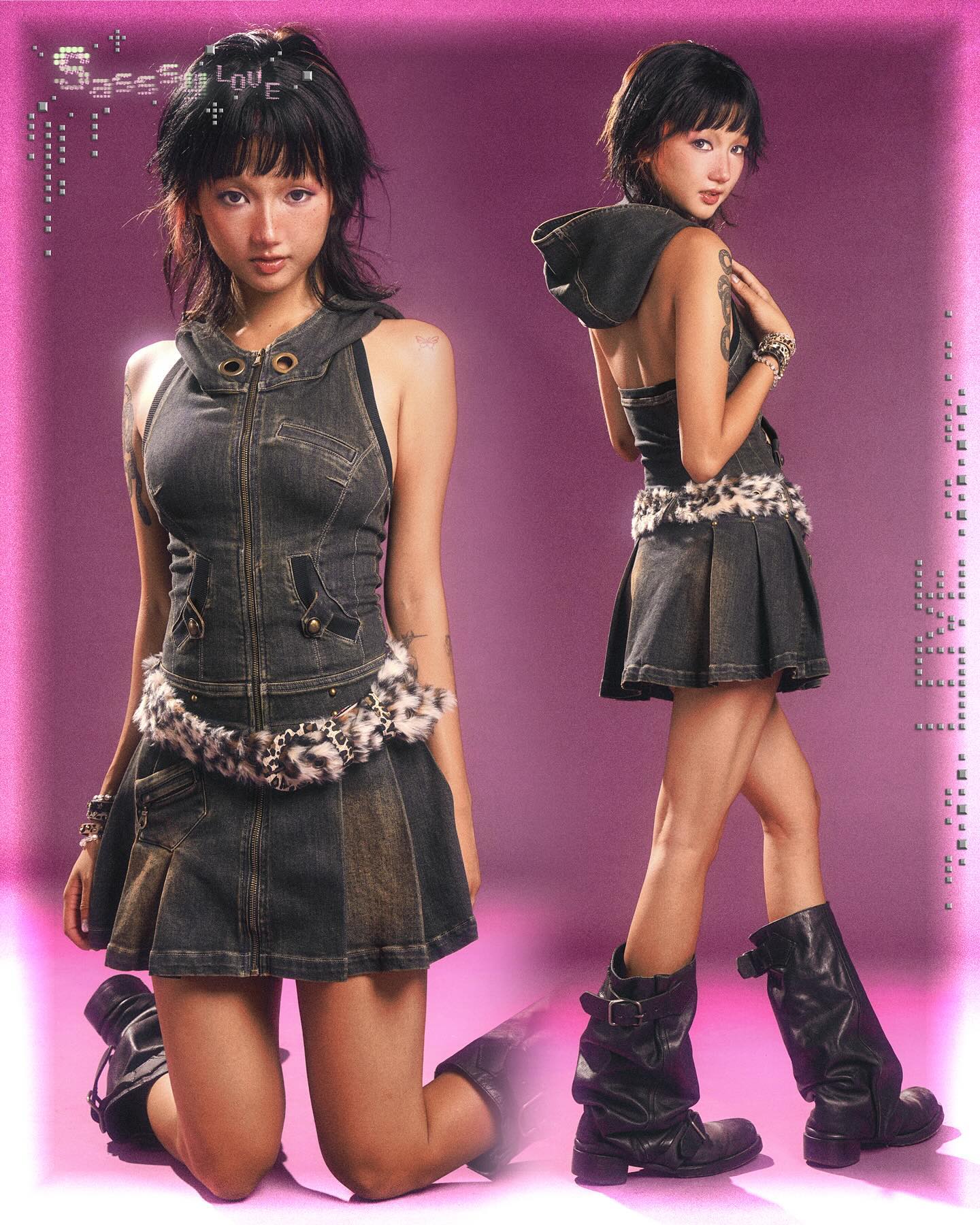the image showcases two identical young women, possibly twins, wearing matching outfits.  they are styled in darkwash denim mini skirts with a denim jacket style bodice and a leopard print belt.  both are wearing tall black boots with a slouchy look. they have similar short hairstyles and pose in a similar crouched position against a pink background. the overall aesthetic is grunge, punk, or alternative fashion, with a youthful and slightly rebellious vibe. the image is a professional, studiostyle photograph.