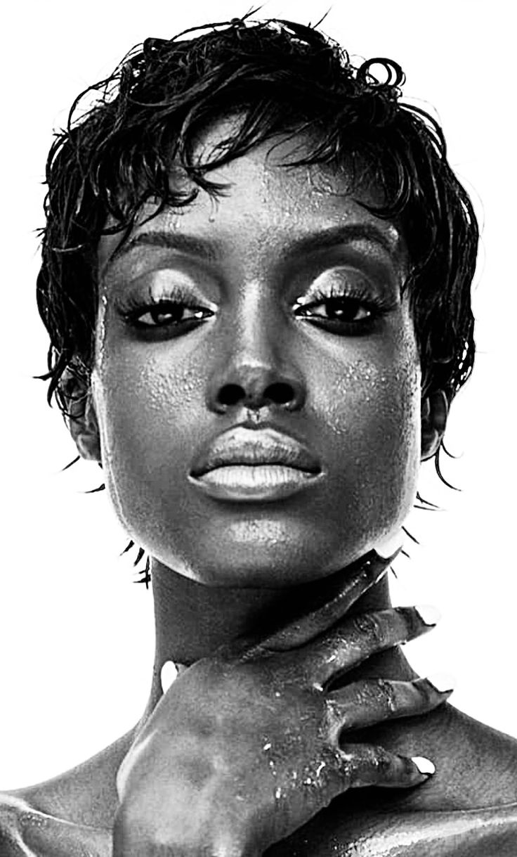 the image is a dramatic black and white closeup portrait of a woman with short, wet hair.  her skin is glistening, possibly from water or oil. she has dark skin and striking features, and her expression is serious and intense.  her hand is placed on her neck, adding to the intimacy and sensuality of the photograph. the lighting is high contrast, emphasizing the textures of her skin and hair.  the overall mood is sophisticated and powerful.