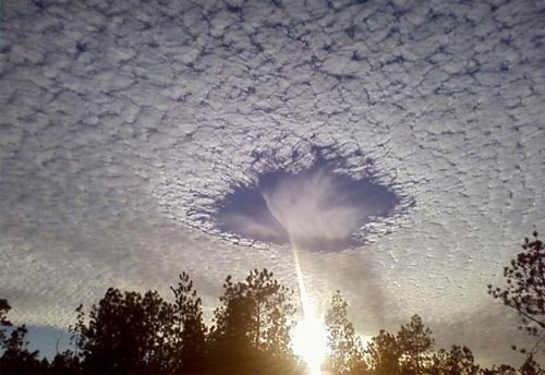 a breathtaking image of a cloud formation in the sky, creating a perfect hole that allows sunlight to shine through. the hole in the clouds is surrounded by a ring of white clouds. the sunlight is shining through the hole and creating a bright beam of light, the sky is a bright blue, and the clouds are a soft white. the image is a stunning example of the beauty and power of nature.