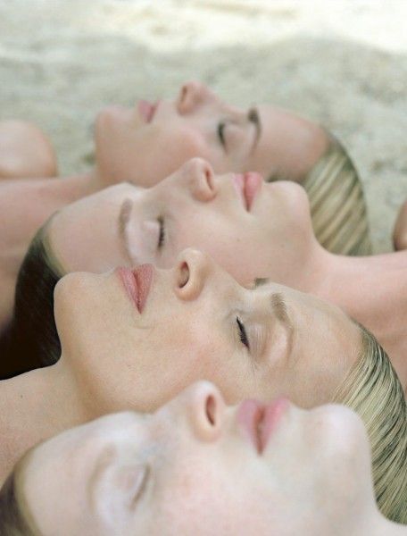 a close up portrait of four women asleep with their eyes closed, laying on top of each other. their skin is clear and smooth, suggesting tranquility and serenity.