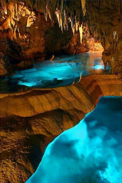 a stunning photo of a cave with a beautiful blue water reflection. the water is crystal clear and reflects the light from the opening of the cave. the rock formations are stunning and create a sense of awe and wonder.