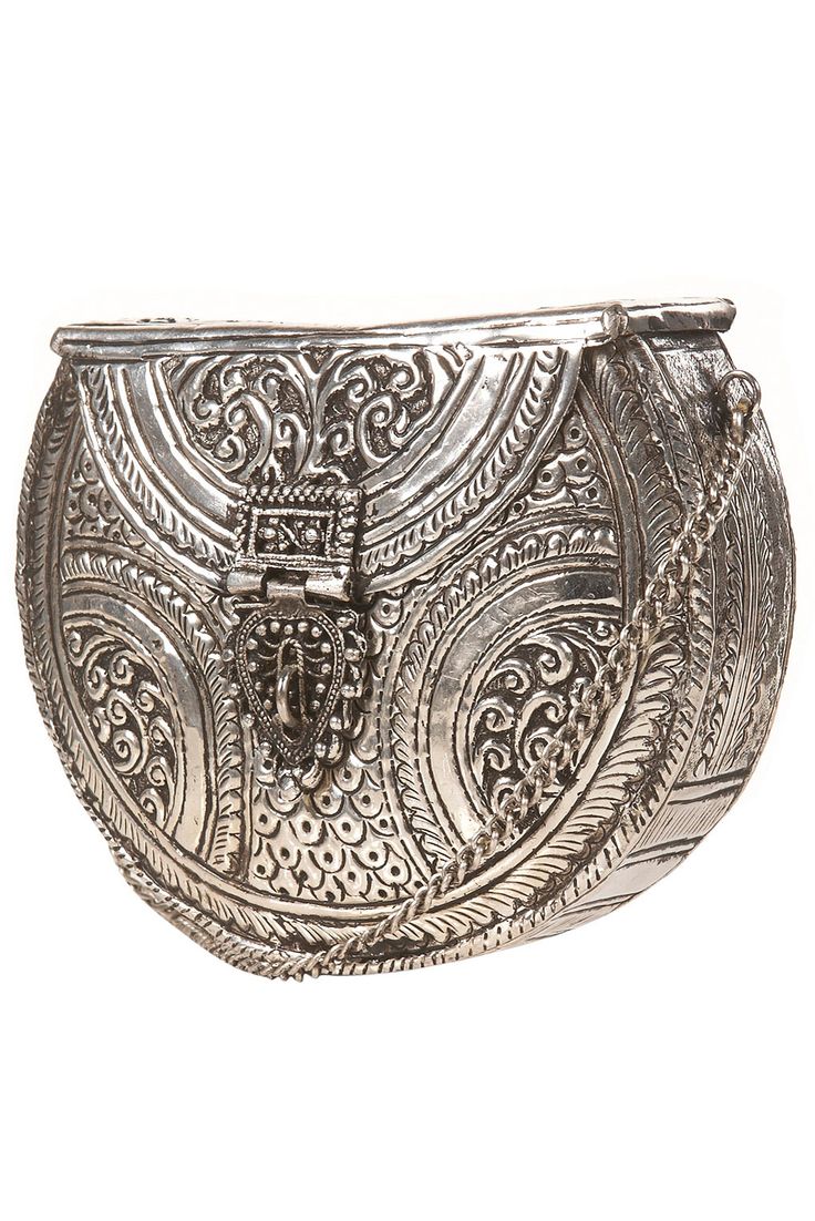 a silver ornate bag with intricate designs. the bag features a fold over clasp and a chain.  the bag is made from metal.