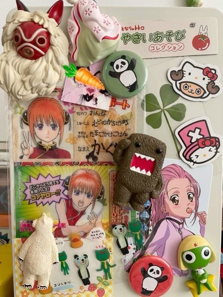 the image shows a collection of various anime and cartoonthemed magnets and stickers attached to a refrigerator. there are several anime characters, including figures and stickers from the gintama series, a domo kun plush, a panda magnet in two colors, hello kitty, a totoro magnet, a polar bear magnet, various frogshaped magnets, a carrot magnet, and a fourleaf clover sticker.