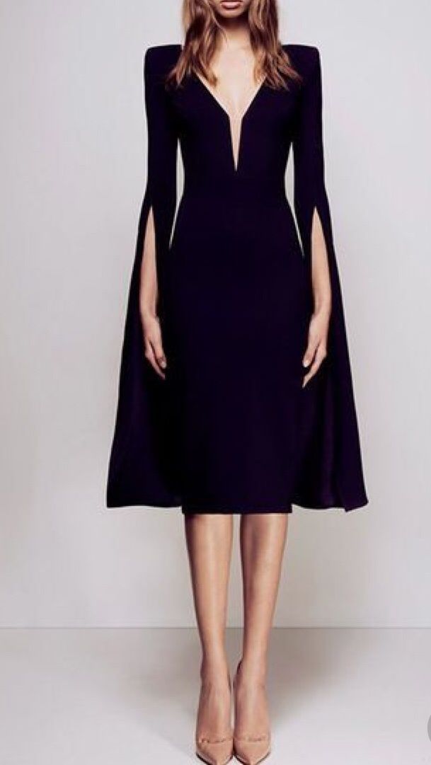 a fulllength studio shot of a model wearing a black midi dress. the dress has long sleeves with slits on the sides, creating a capelike effect. it features a vneckline and a fitted silhouette that flares slightly at the hem. the model is wearing nudecolored high heels and her hair is styled in a straight, middleparted manner. the background is plain and uncluttered, focusing all attention on the dress and the model. the overall image conveys elegance and sophistication.
