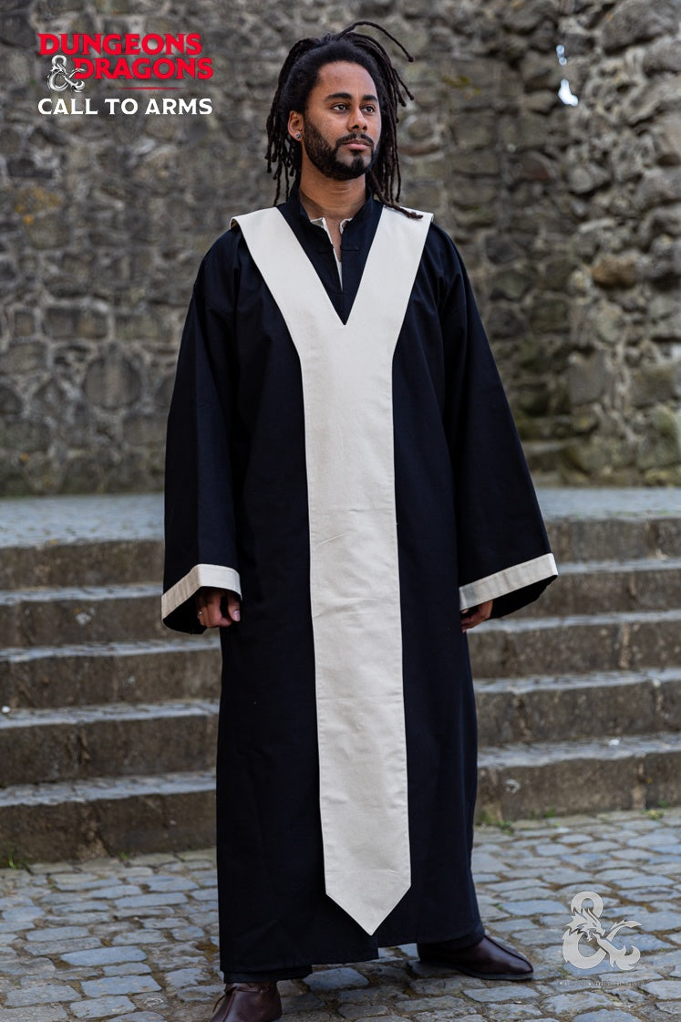 a man with dreadlocks and a beard stands in a long black robe with white trim down the front and at the sleeves. he is standing on cobblestones in front of a stone staircase and wall. logos for dungeons and dragons "call to arms" are in the top left and bottom right corners. he is wearing brown shoes.