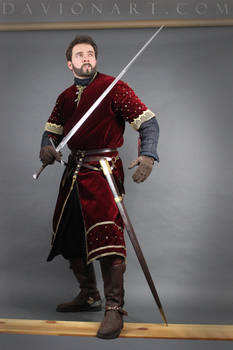 the image shows a man dressed in a meticulously detailed medievalstyle costume. he is wearing a rich burgundy velvet tunic with gold embroidery, dark pants, leather boots, and gloves.  he holds a longsword and seems to be in a posed shot, possibly for a historical recreation, fantasy portrayal, or a photoshoot. the background is a simple gray wall, and a wooden plank is positioned at his feet. the overall style suggests a knight or highranking soldier from the medieval or renaissance period. the image quality and composition are professional, possibly from a stock photo website like davionart.