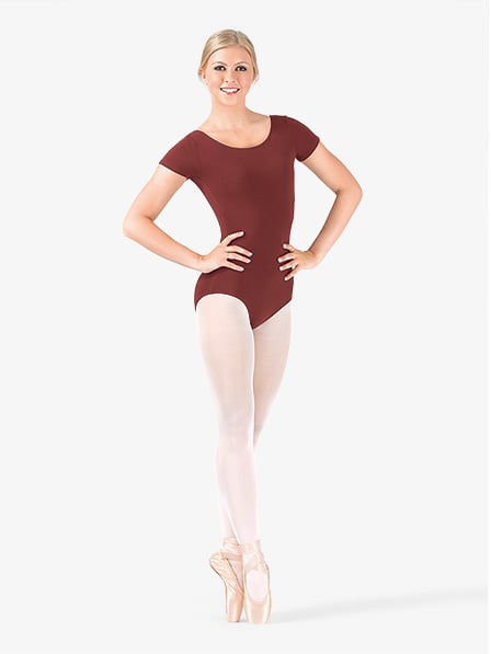 the image shows a young woman, a ballet dancer, wearing a maroon shortsleeved leotard and white tights. she is standing in a graceful pose, with her hands on her hips, and wearing pointe shoes.  the background is plain white, focusing attention on the dancer and her attire. the overall impression is one of elegance and professionalism related to ballet dance.