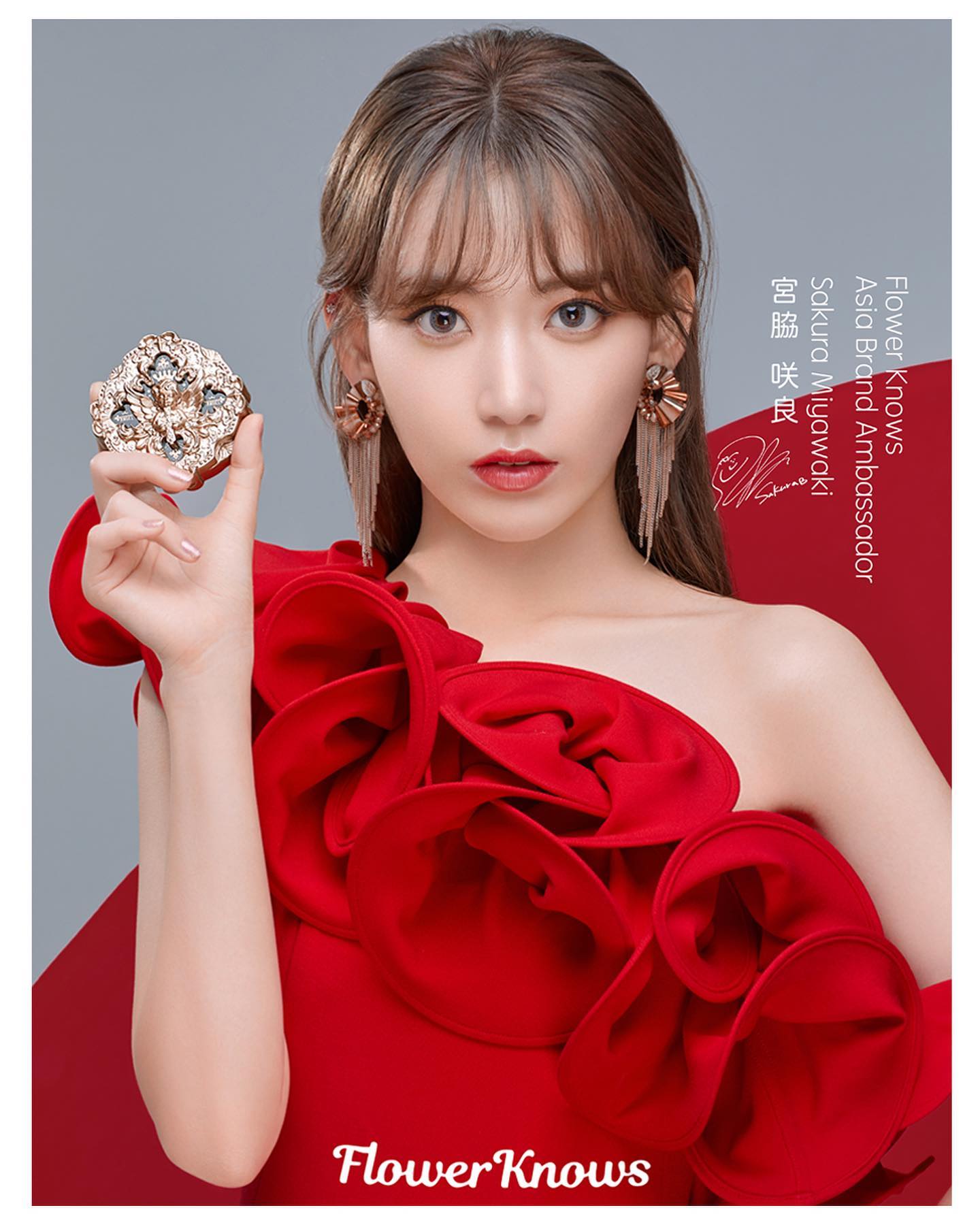 a portrait of sakura miyawaki, a japanese idol, promoting flower knows cosmetics. she is wearing a red oneshoulder dress and holding a gold compact. the background is red and white.