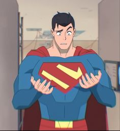 a cartoon image of superman from the chest up.  he is looking down at his chest with a surprised and concerned expression. his hands are outstretched and touching the bottom of the "s" symbol on his chest. his costume looks to be the classic blue suit with red cape, red boots and a red belt with a gold buckle. he is standing in a room with light blue walls.