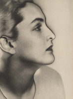 the image is a striking black and white portrait of a woman, shown in profile view. her face is the primary focus, filling most of the frame. the soft lighting and subtle shadows create a sense of depth and highlight her elegant features. her expression is serene and slightly pensive, with her gaze directed towards the right. the style suggests a classic portrait from the 1920s or 1930s, possibly art deco influenced by the soft lines and focus on beauty.  the background is plain and unblemished, keeping all the attention on the subject. the overall mood is one of timeless beauty and grace.