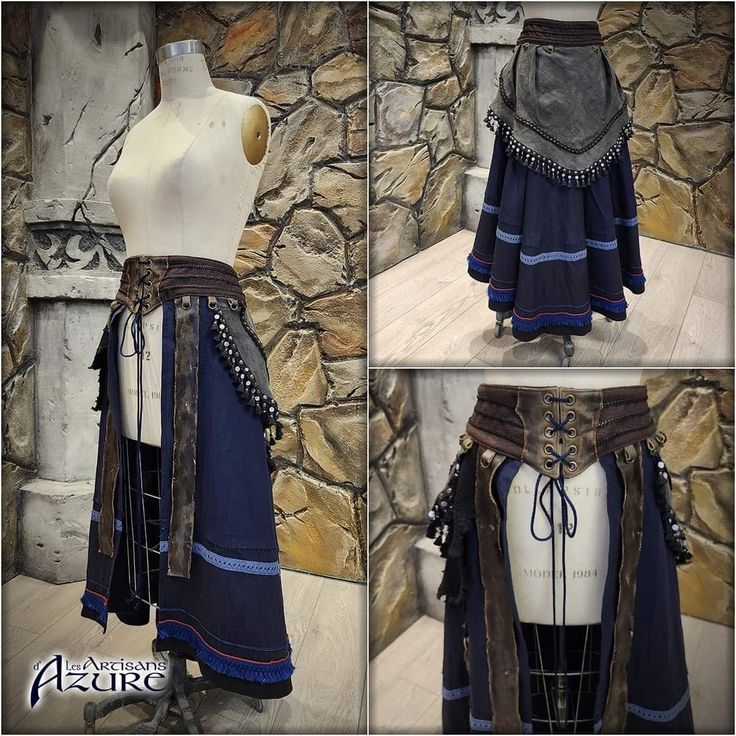 the image shows a detailed view of a handcrafted, long skirt designed in a medieval or fantasy style.  it features a dark blue base fabric, layered design, and a prominent brown leather corsetstyle belt adorned with metal accents and tassels.  the skirt is shown on a mannequin from several angles. the skirt’s style incorporates a mix of textures and details, including decorative stitching and embellishments. the backdrop is a stone wall, suggesting a historical or fantasy setting. a watermark of "les artisans azure" is visible on the image. the different angles showcase the craftsmanship and the overall design of the skirt.