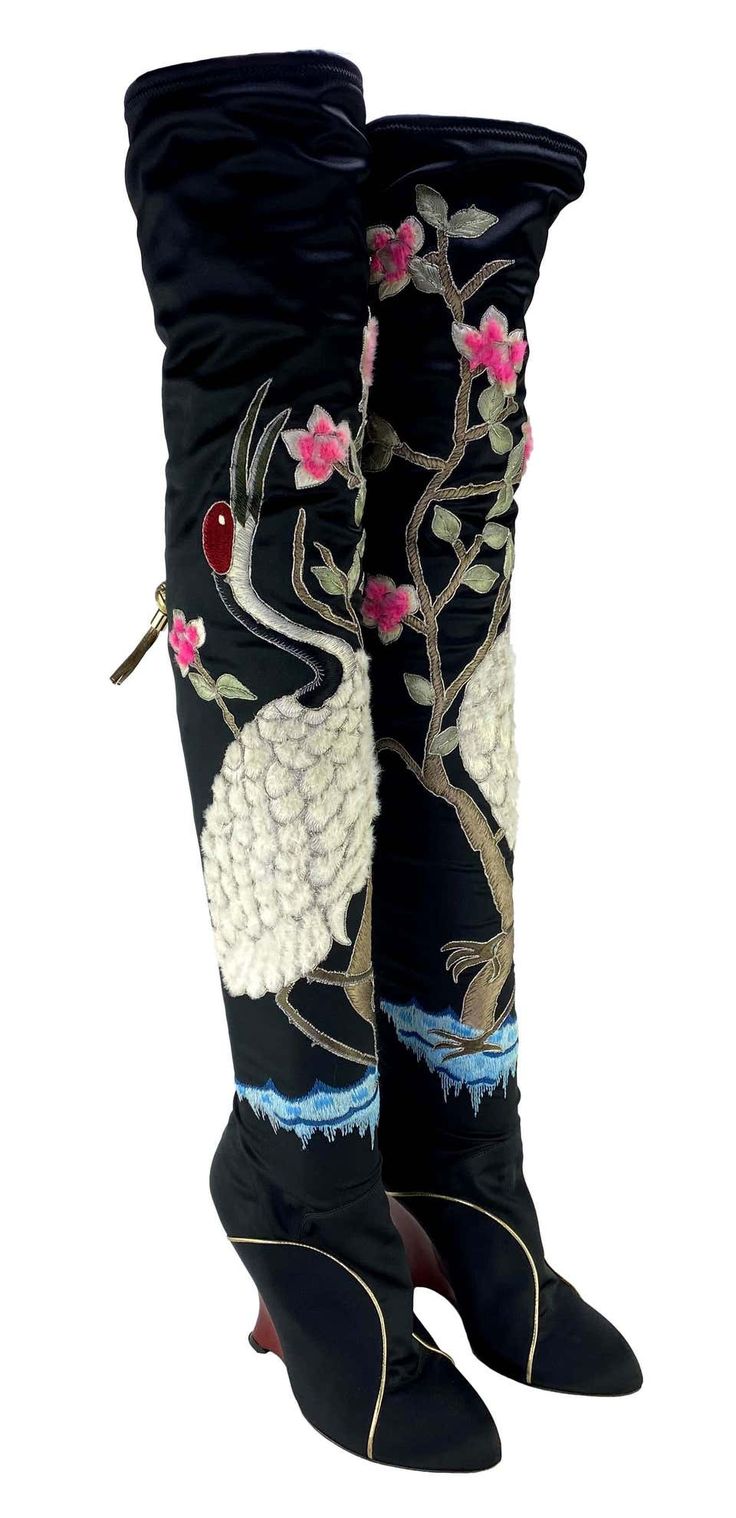 a pair of women's black satin high heeled boots, with embroidered cranes and floral patterns. the boots have a wedge heel.