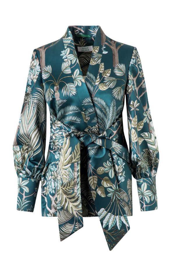 teal green satin wrap blouse with a tropical floral print.  the blouse has long puffed sleeves and a tie waist. the print features palm leaves, other tropical foliage, and trees. the blouse is styled with a relaxed, kimonolike silhouette. the overall style is elegant and luxurious.