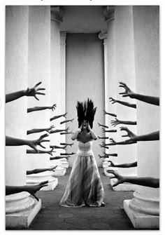 a woman stands in a hall with columns on either side, her hands up to her face screaming. there are many ghostly hands reaching out from the columns towards the woman, as if attempting to grab her. the image is in black and white which contributes to the creepy and surreal feeling of the image.