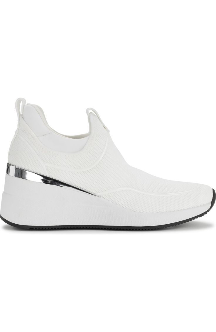 the image shows a single white women's sneaker with a hidden wedge heel.  the shoe is a slipon style, made of a breathable knit fabric. it has a minimalist design with a metallic silver accent at the heel. the sole is white with a black bottom. the shoe is presented on a white background.