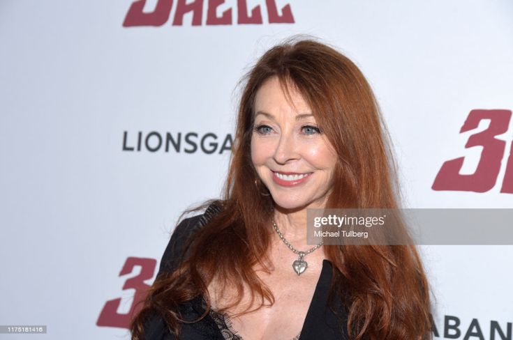a woman with long red hair smiles for the camera as she attends a movie premiere on the red carpet in hollywood, california.