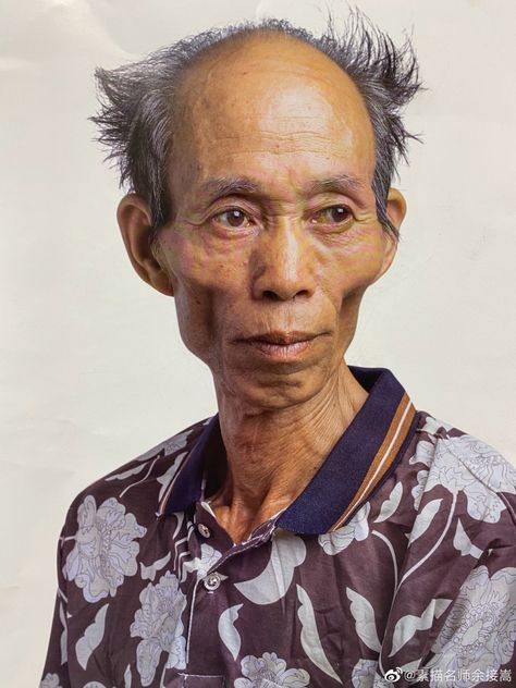 a closeup portrait of an elderly man with thin build and weathered skin. he has a receding hairline and sparse, spiky hair. his face is heavily lined with wrinkles, indicative of age. he is wearing a buttondown shirt with a dark floral pattern and a contrasting collar. the background is plain and light.