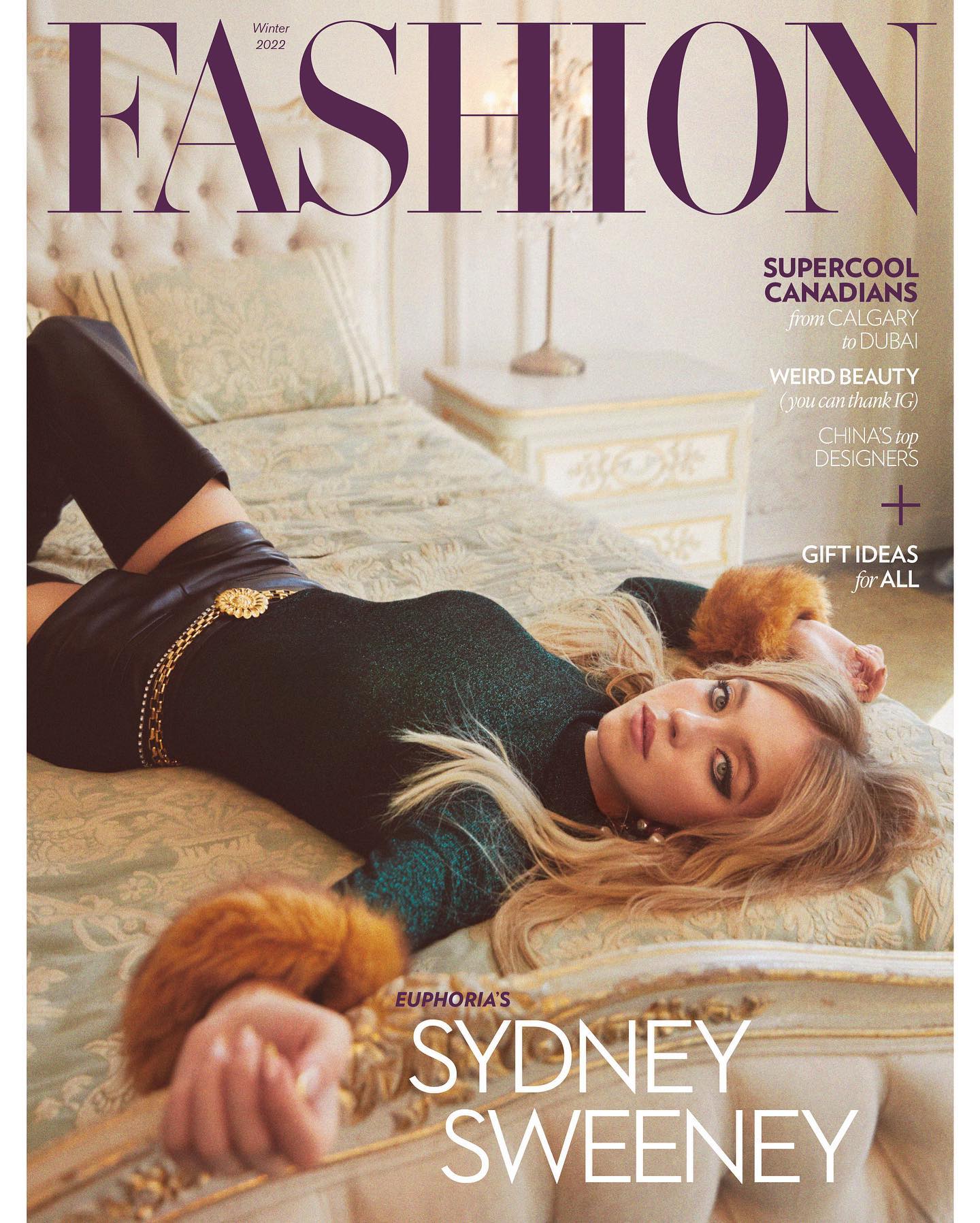 he image is a magazine cover for a publication called "fashion," showcasing the actress sydney sweeney as the cover model. the cover features a stylish layout, including the title of the magazine in bold purple lettering. the winter 2022 issue focuses on supercool canadians, weird beauty, and chinese top designers, along with a gift guide.  sydney sweeney lies on a luxurious bed, wearing a dark green longsleeved top and black leather pants and boots.  her blonde hair is styled loosely around her, and she has on fur cuffs. the overall aesthetic is elegant and stylish, consistent with a highfashion magazine.
