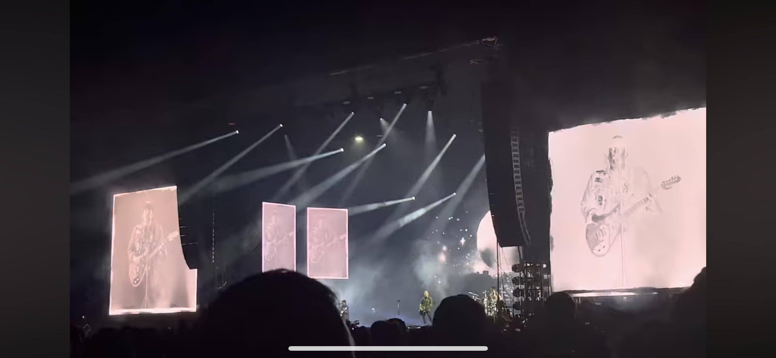 a concert stage with a band performing live in front of a large crowd. the stage is lit with many spotlights and is set up with sound equipment, including microphones, speakers, and amplifiers.  the crowd is excited and energized, enjoying the music. the band is playing rock music.
