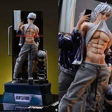 he image shows two different angles of the same anime figure. the figure is a muscular male with white hair, wearing gray athletic clothing. in one angle, he's posed taking a selfie, showing off his muscular physique. the other angle shows the figure from a slightly different perspective, still highlighting his muscular build.  both images show the figure displayed on a dark base, implying it's a collectible or statue. the background is blurred, with only part of a wall and what appears to be part of a display set visible.  the overall style is that of an action figure collectible, likely targeted towards fans of anime and body building aesthetics.