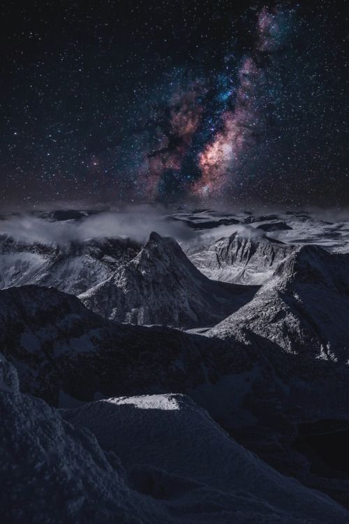a panoramic view of a majestic mountain range under a breathtaking starry night sky. the milky way galaxy stretches across the heavens, casting a soft glow upon the snowcapped peaks. the clouds drift lazily across the scene, adding a touch of mystery and ethereal beauty. the vastness of the universe is palpable, as the stars twinkle like distant diamonds. it's a truly aweinspiring sight that evokes a sense of wonder and insignificance in the face of nature's grandeur.