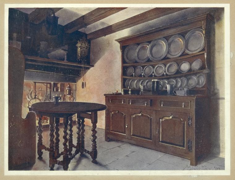 an image of a vintage kitchen interior. a wooden plate rack cabinet filled with shiny plates and dishes is positioned against the right wall. to the left, a round wooden table with twisted legs stands on a stone floor. in the background, a fireplace with utensils hanging above it is visible, with pottery on the shelf. overhead wooden beams are visible, and a hanging clock is on the wall near the fireplace.
